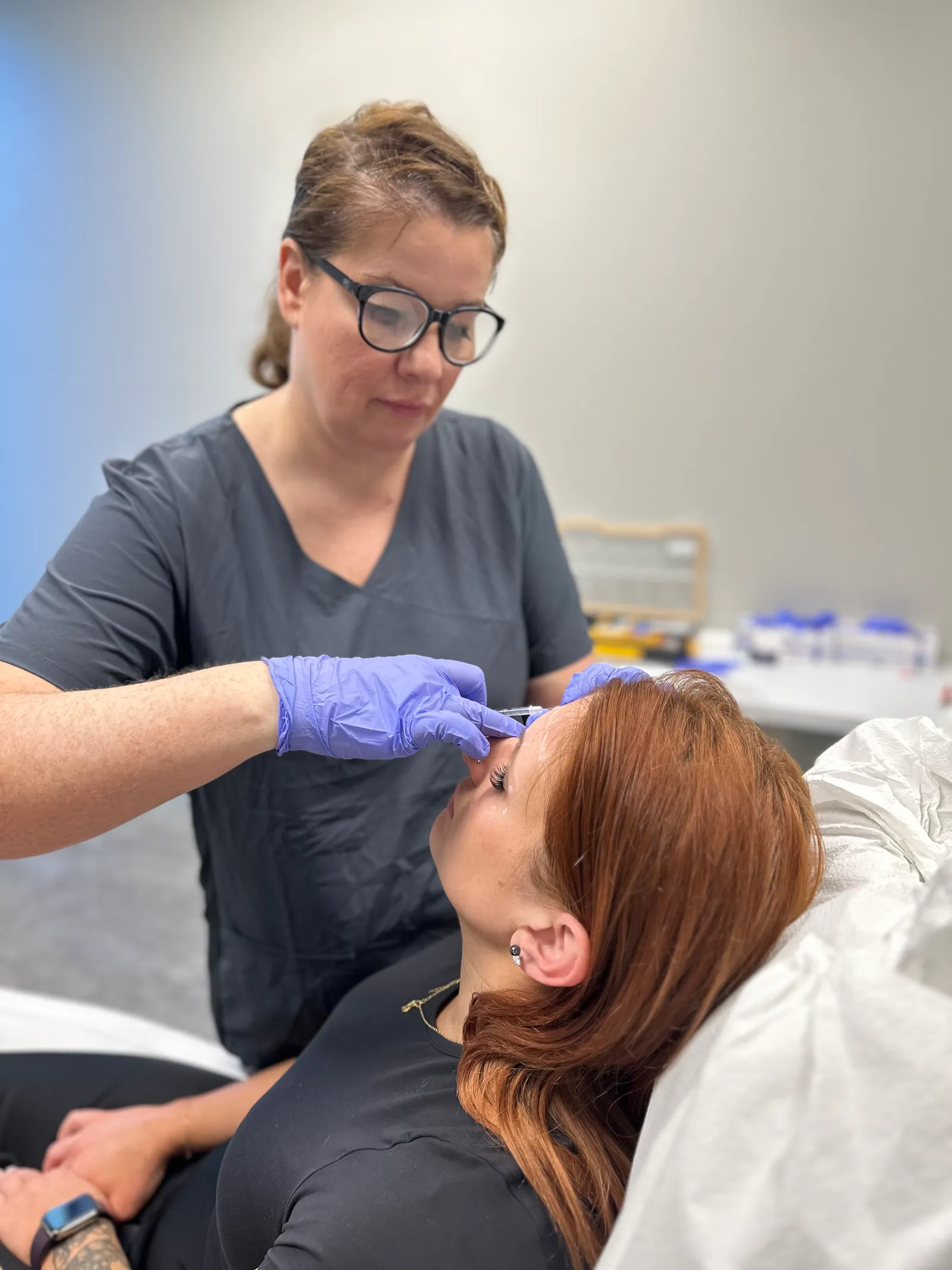 A NEXT STEP participant in gray scrubs practices with a red-haired live model in Atlanta
